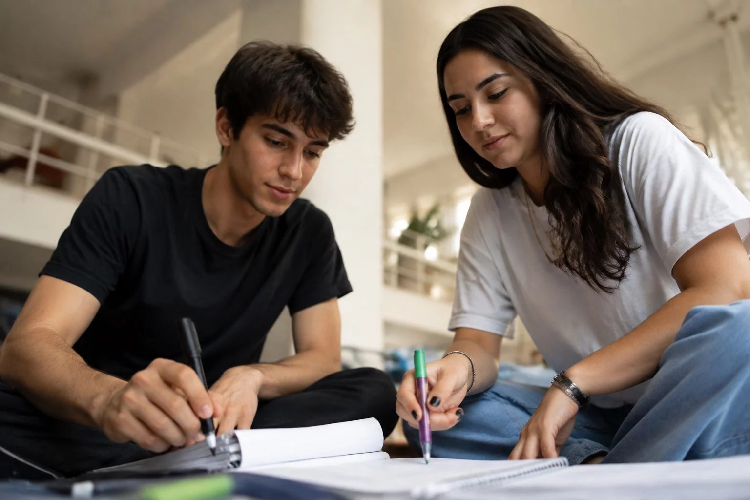 Dois estudantes preparando um debate com cadernos e marcadores